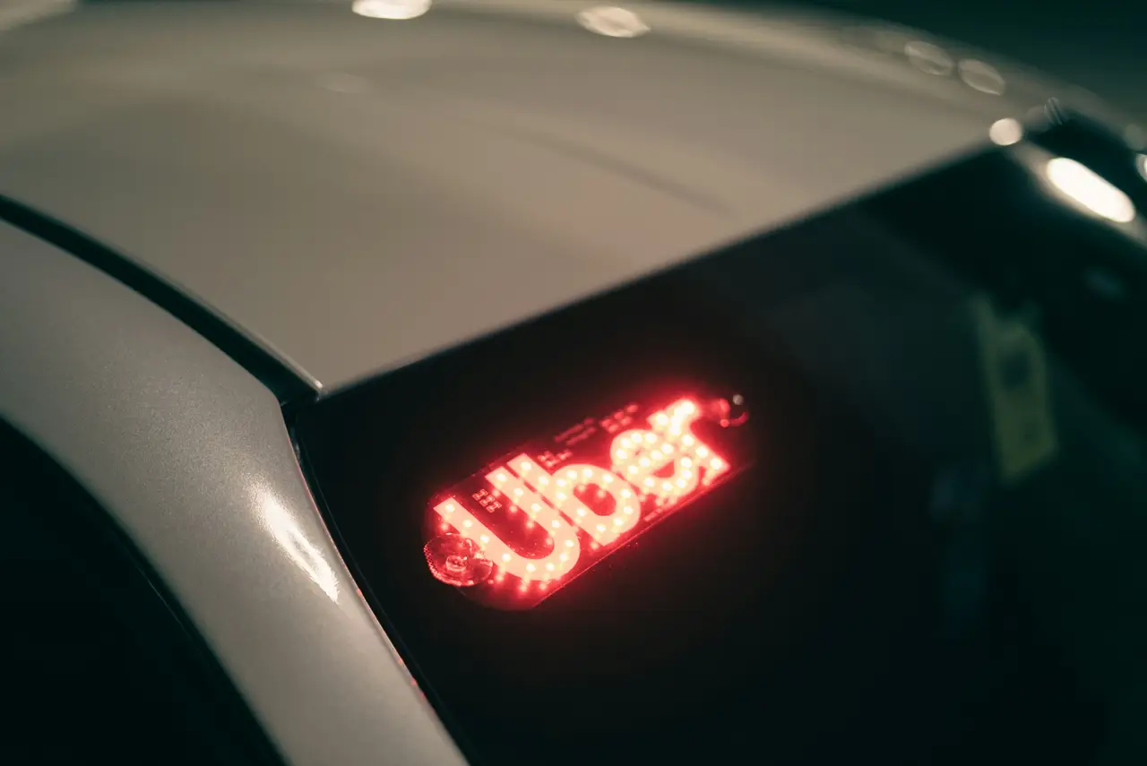 Teto de um carro de aplicativo à noite, com o letreiro aceso no para-brisa