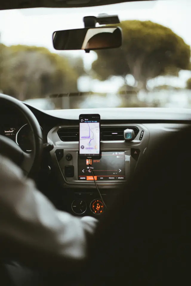 Painel de carro com celular no suporte mostrando a rota de uma corrida